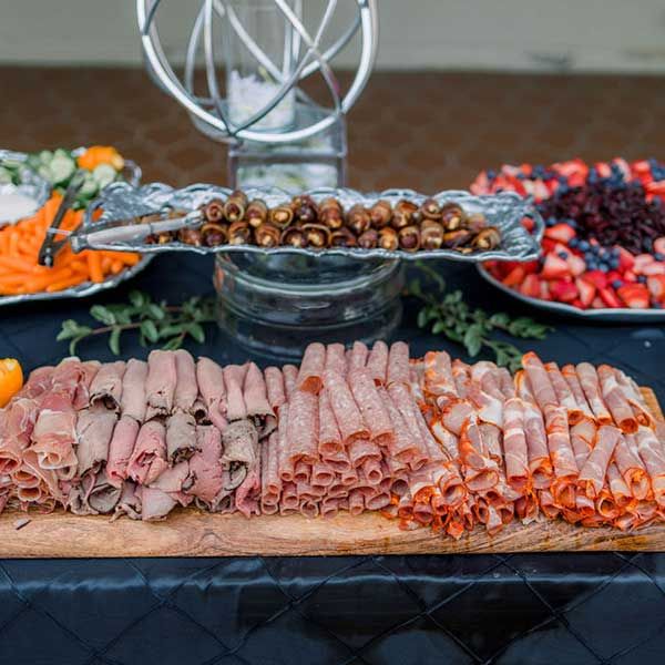 Sliced meats and fruits are prepqred prior to guests arriving.